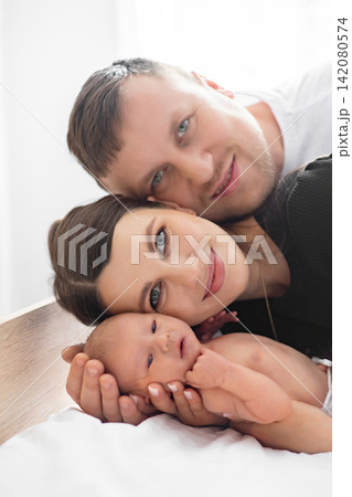 A loving family portrait featuring parents embracing their newborn baby with tenderness and joy A loving family portrait featuring parents embracing their newborn baby with tenderness and joy 142080574