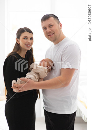 A smiling caucasian couple proudly holds their newborn baby, celebrating a new beginning together in a bright, clean environment A smiling caucasian couple proudly holds their newborn baby, celebrating a new beginning together in a bright, clean environment 142080607