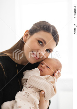 A loving mother cradles her newborn infant, sharing a tender moment of connection and affection in a bright, natural setting A loving mother cradles her newborn infant, sharing a tender moment of connection and affection in a bright, natural setting 142080610