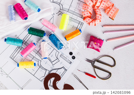 Sewing patterns, threads, scissors, templates and needles on a work table top view 142081096
