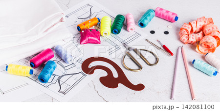 Sewing patterns, threads, scissors, templates and needles on a work table web banner 142081100