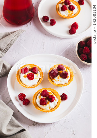 Fresh raspberries and cottage cheese in tartlets on a plate on the table vertical view Fresh raspberries and cottage cheese in tartlets on a plate on the table vertical view 142081104