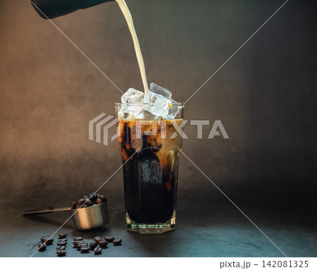 Pouring milk make latte coffee with ice roasted coffee beans on black background Pouring milk make latte coffee with ice roasted coffee beans on black background 142081325