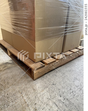 ラップフィルムで荷崩れ防止された段ボール箱と木製パレット ラップフィルムで荷崩れ防止された段ボール箱と木製パレット 142081555