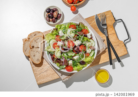 Fresh Greek salad with feta cheese, olives and vegetables in a plate on a white table 142081969