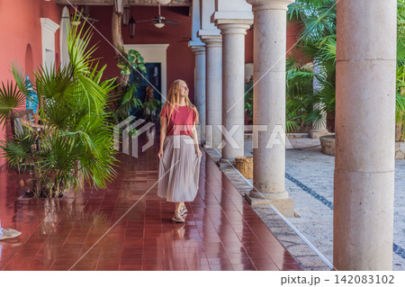 Female tourist walks and twirls through colonial arches, tiled floors and stone details, showing Mexico travel, culture and elegant vacation style concept Female tourist walks and twirls through colonial arches, tiled floors and stone details, showing Mexico travel, culture and elegant vacation style concept 142083102