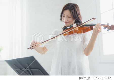 自宅でバイオリンを練習する女性 自宅でバイオリンを練習する女性 142084012