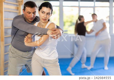Young woman and adult man training self-defense techniques Young woman and adult man training self-defense techniques 142084555
