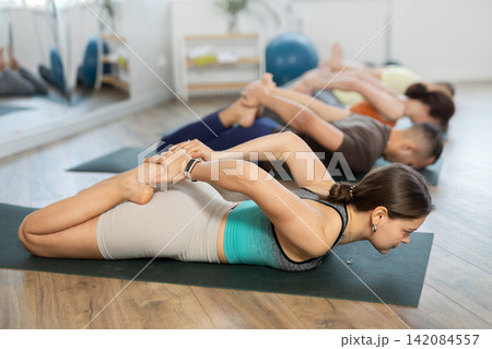 Lovers of active lifestyle on yoga mat perform doing Ardha Bhekasana, frog pose in gym 142084557