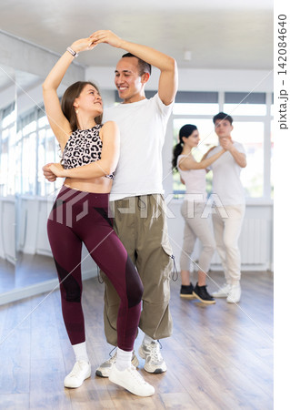 Dance training in group - young men and women dance salsa or bachata in dance studio Dance training in group - young men and women dance salsa or bachata in dance studio 142084640