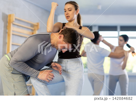 Self defense lesson - woman learns to fight back an attacking man Self defense lesson - woman learns to fight back an attacking man 142084682