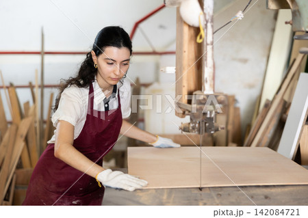 Girl cutting board in taller workshop Girl cutting board in taller workshop 142084721