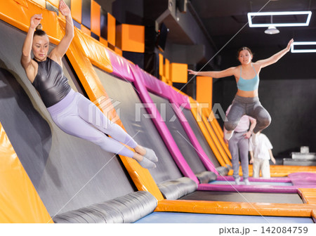 Adult woman trains jumping in trampoline center 142084759