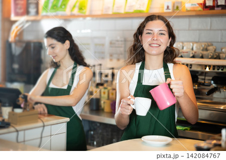 Young woman pouring coffee in cafe 142084767