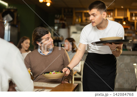 Waiter guy brings an order for men 142084768
