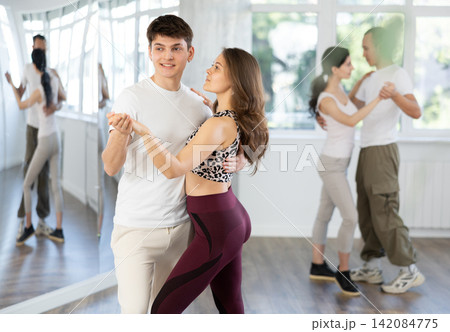 Dance studio - students in casual clothes learn to dance tango Dance studio - students in casual clothes learn to dance tango 142084775