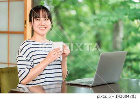 ワーケーション,滞在先で仕事をする一息つく,休憩にコーヒーを飲むフリーランスの女性 142084783