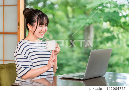 ワーケーション,滞在先で仕事をする一息つく,休憩にコーヒーを飲むフリーランスの女性 ワーケーション,滞在先で仕事をする一息つく,休憩にコーヒーを飲むフリーランスの女性 142084785