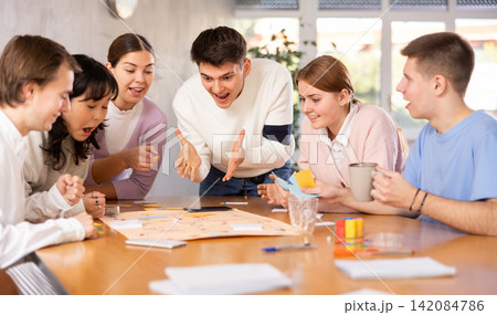 Carefree student playing board game with friends at table 142084786