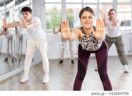 Group of women and men enjoying active dance movement in modern studio Group of women and men enjoying active dance movement in modern studio 142084790