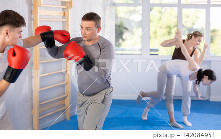 Middle-aged man training boxing with partner during sports classes Middle-aged man training boxing with partner during sports classes 142084951