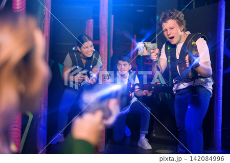 Two guys and one girl running and dodging while playing lasertag 142084996
