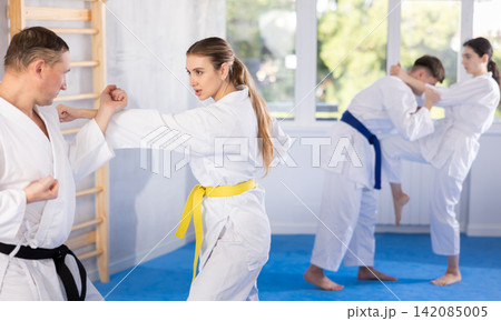 Adult man and young woman training karate techniques Adult man and young woman training karate techniques 142085005