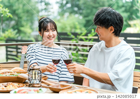 ウッドデッキ,テラス席,バルコニー席で食事するカップル,夫婦(グランピング・ベランピング) ウッドデッキ,テラス席,バルコニー席で食事するカップル,夫婦(グランピング・ベランピング) 142085017