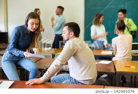 Students of university chatting on break sitting at desks 142085076