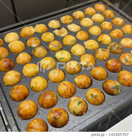 Takoyaki, a popular Japanese street food, are crispy round dough balls filled with octopus, tempura bits, and pickled ginger, topped with takoyaki sauce, bonito flakes, and aonori. Takoyaki, a popular Japanese street food, are crispy round dough balls filled with octopus, tempura bits, and pickled ginger, topped with takoyaki sauce, bonito flakes, and aonori. 142085767
