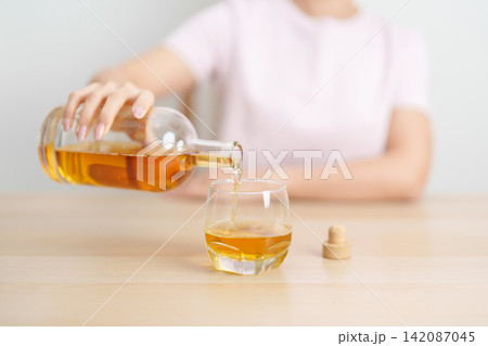 woman pour whiskey into a glass on table, suffering from alcohol addiction, alcoholism concept. depicting emotional distress, depression, substance abuse problem, unhealthy lifestyle and mental health woman pour whiskey into a glass on table, suffering from alcohol addiction, alcoholism concept. depicting emotional distress, depression, substance abuse problem, unhealthy lifestyle and mental health 142087045