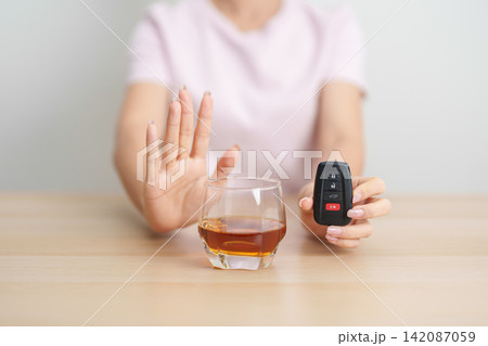Responsible woman reject a drink before driving for road safety, Man making stop hand gesture to refuse a glass of whiskey and car remote. Avoid drink and drive, Drunk Driving Law concept 142087059