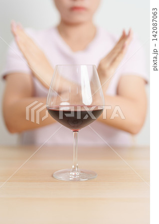 woman making stop hand gesture to refuse a glass of Wine, Healthy man say no to alcohol drink, stop alcoholism and addiction concept. Responsible man reject a drink before driving and quit booze 142087063
