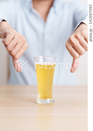 man show thumb down hand gesture to refuse a glass of Beer, Healthy man say no to alcohol drink, stop alcoholism and addiction concept. Responsible man reject a drink before driving and quit booze 142087093
