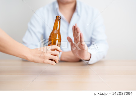 man making stop hand gesture to refuse a bottle of Beer, Healthy man say no to alcohol drink, stop alcoholism and addiction concept. Responsible man reject a drink before driving and quit booze 142087094