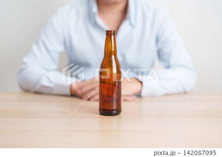 man with bottle of Beer on table, suffering from alcohol addiction and alcoholism concept. depicting emotional distress, depression, substance abuse problem, unhealthy lifestyle and mental health man with bottle of Beer on table, suffering from alcohol addiction and alcoholism concept. depicting emotional distress, depression, substance abuse problem, unhealthy lifestyle and mental health 142087095