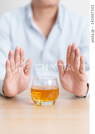 Man making stop hand gesture to refuse a glass of whiskey, Healthy man say no to alcohol drink, stop alcoholism and addiction concept. Responsible man reject a drink before driving and quit booze 142087101
