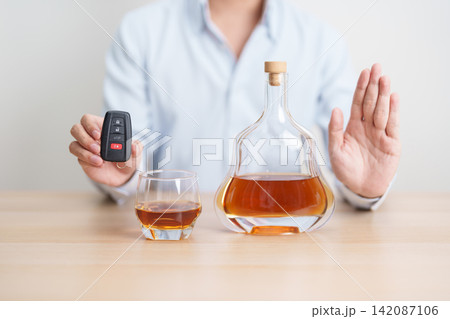 Responsible man reject a drink before driving for road safety, Man making stop hand gesture to refuse a glass of whiskey and car remote. Avoid drink and drive, Drunk Driving Law concept Responsible man reject a drink before driving for road safety, Man making stop hand gesture to refuse a glass of whiskey and car remote. Avoid drink and drive, Drunk Driving Law concept 142087106