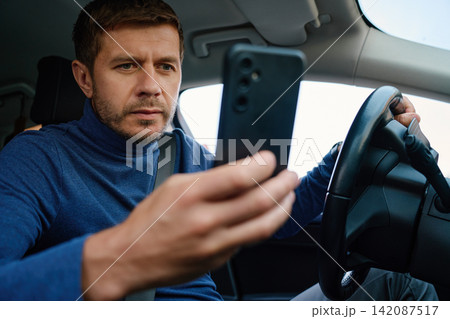 Man Using Smartphone While Sitting in Car Before Driving Man Using Smartphone While Sitting in Car Before Driving 142087517