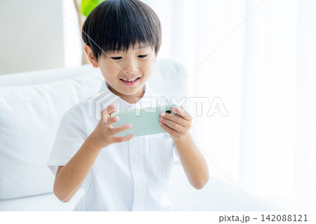 スマホを操作する小学生の男の子 スマホを操作する小学生の男の子 142088121