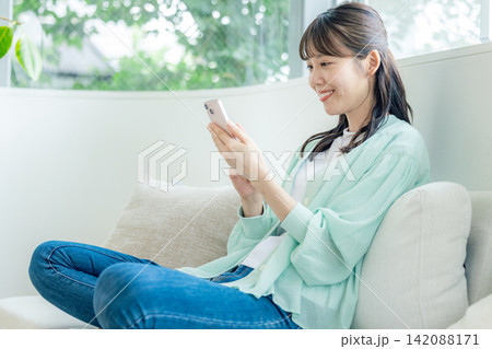 ソファーでスマホを使う女性 ソファーでスマホを使う女性 142088171
