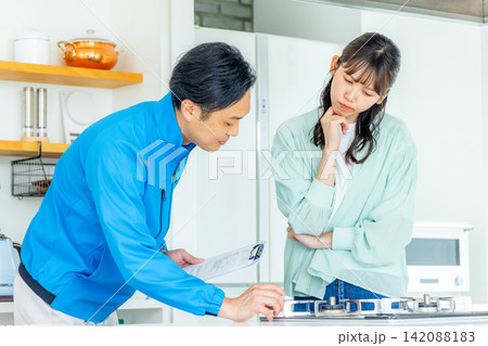 キッチンで困った女性と点検に来た作業員 キッチンで困った女性と点検に来た作業員 142088183