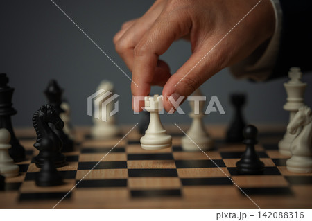 business hand positioning white chess rook on chessboard, tactical move 142088316
