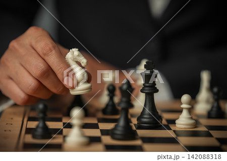 business hand arranging chess knight on wooden board, game strategy business hand arranging chess knight on wooden board, game strategy 142088318