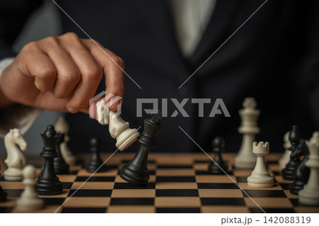 business hand holding white chess knight taking black king, strategy concept business hand holding white chess knight taking black king, strategy concept 142088319
