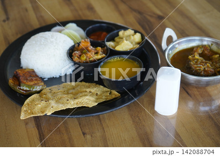 Authentic Indian Bengali fish thali meal platter with rice dal curries and salt shaker on a wooden table Authentic Indian Bengali fish thali meal platter with rice dal curries and salt shaker on a wooden table 142088704