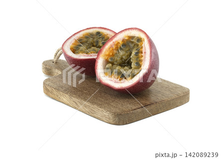 Fresh passion fruit cut in half on a wooden cutting board, showcasing its seeds 142089239