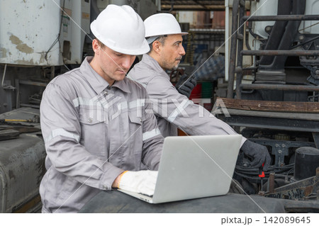 Two workers troubleshooting machinery with laptop on site for efficient maintenance Two workers troubleshooting machinery with laptop on site for efficient maintenance 142089645