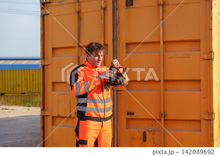 Construction worker preparing safety gear outdoors at storage site. 142089692