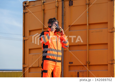 Worker wearing safety gear inspecting hazardous environment outdoors. 142089702